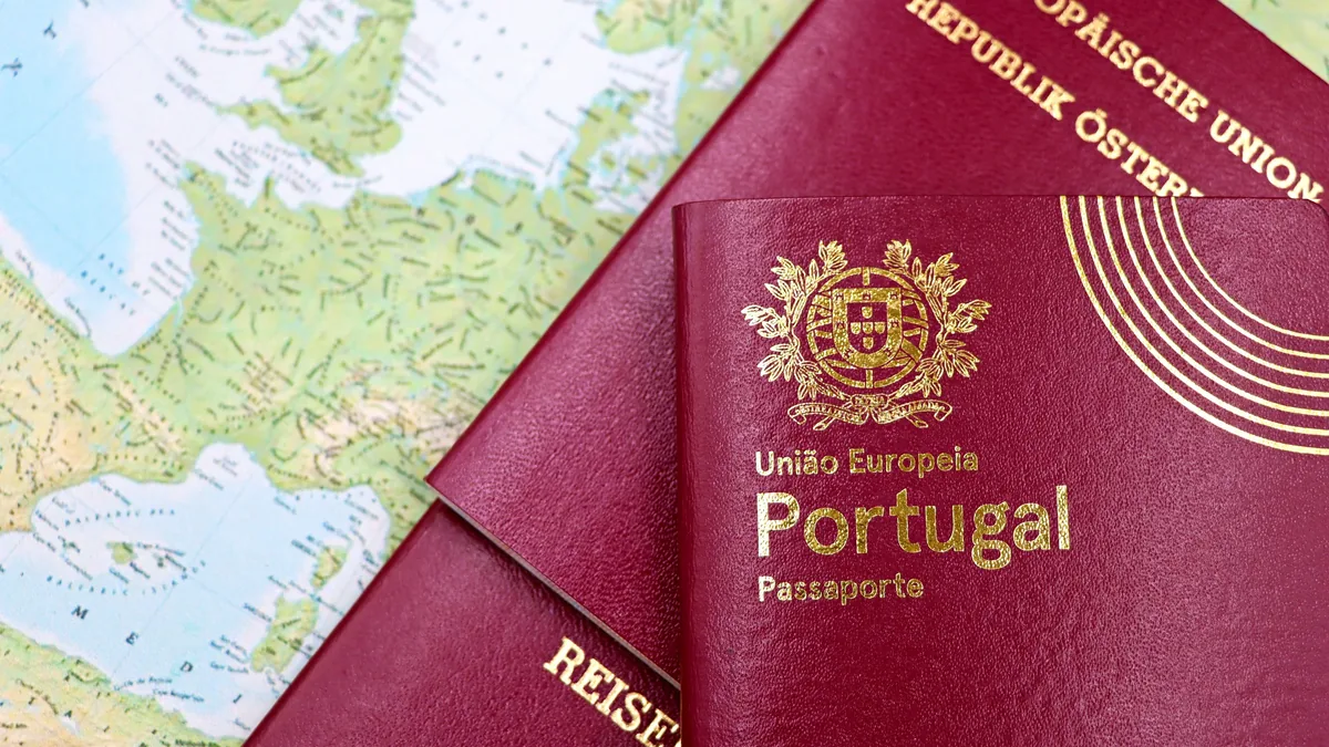 Two red Portuguese passports on top of a map of Europe.